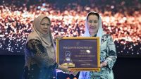 Wakil Gubernur Sulawesi Tengah dr. Reny A. Lamadjido, menyerahkan Paritrana Award kategori pemerintah kabupaten/kota terbaik kepada Wakil Walikota Palu Imelda Liliana Muhidin.
