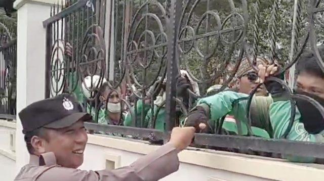 Anggota POLDA Sulteng, menyalami satu-satu pengemudi online dari balik pagar pembatas kantor DPRD Sulteng (aksi demonstrasi masih berlangsung).