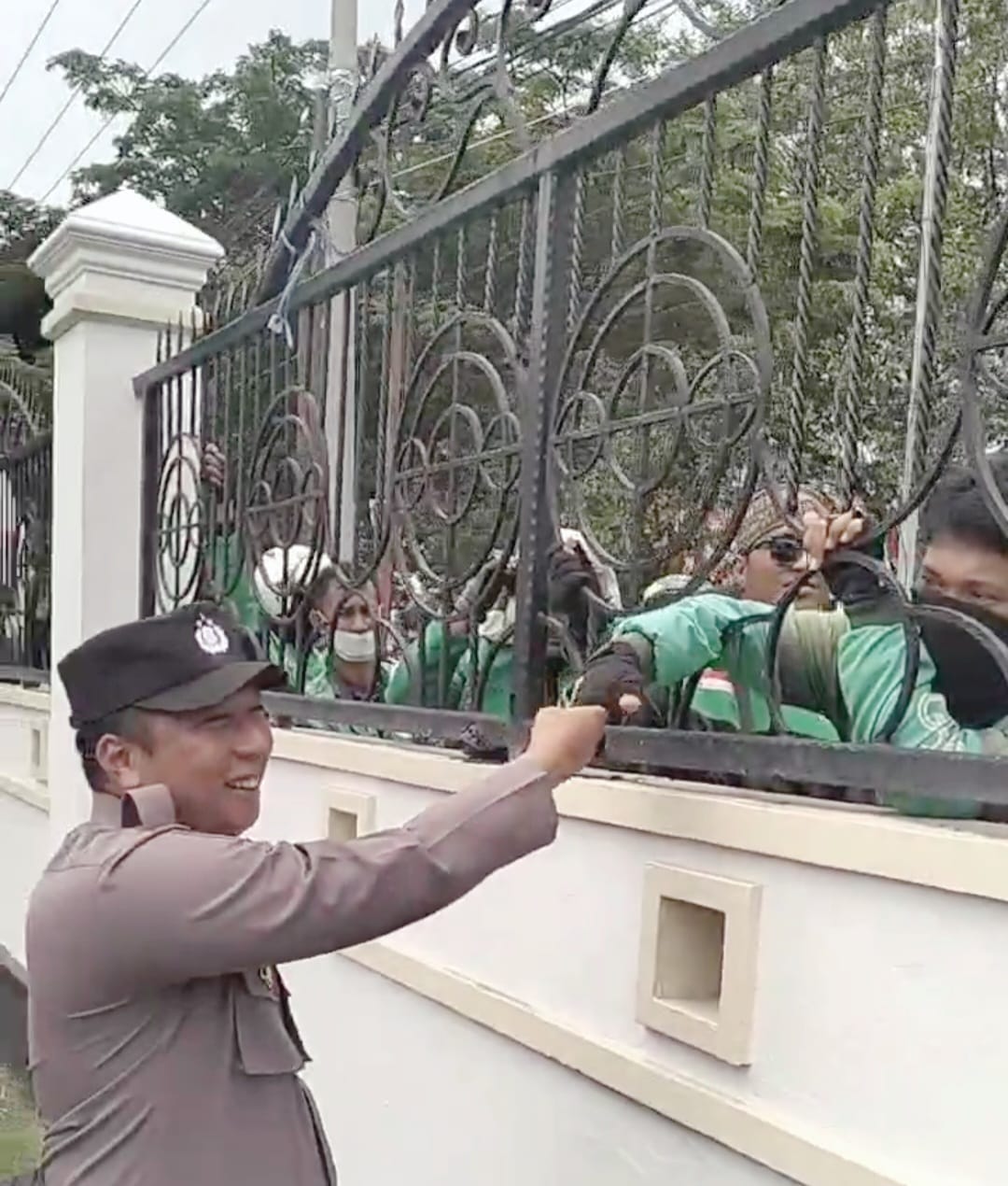Anggota POLDA Sulteng, menyalami satu-satu pengemudi online dari balik pagar pembatas kantor DPRD Sulteng (aksi demonstrasi masih berlangsung).